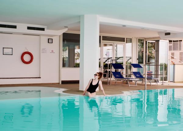 Frau im Hallenbad mit Liegestühlen.
