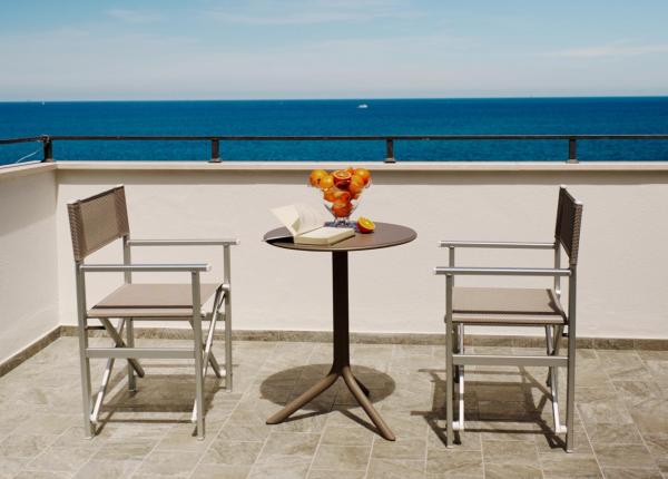 Terrasse mit Meerblick, zwei Stühle, Tisch mit Buch und Obst.