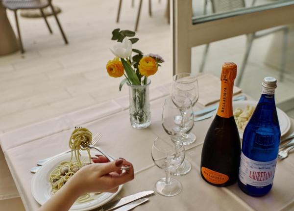 Tisch mit Meerblick, Teller mit Spaghetti, Wein und Wasser.
