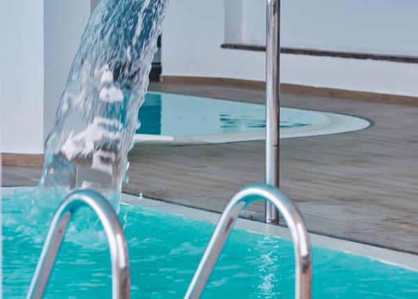 Innenpool mit Wasserfall und Metallleiter.