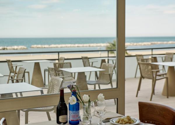 Ristorante con vista mare, tavolo apparecchiato con vino e piatti di pasta.
