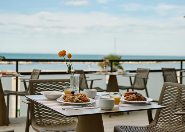 Colazione all'aperto con vista sul mare, croissant e succo d'arancia.