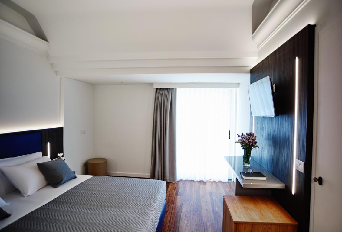 Camera moderna con letto, TV e fiori.