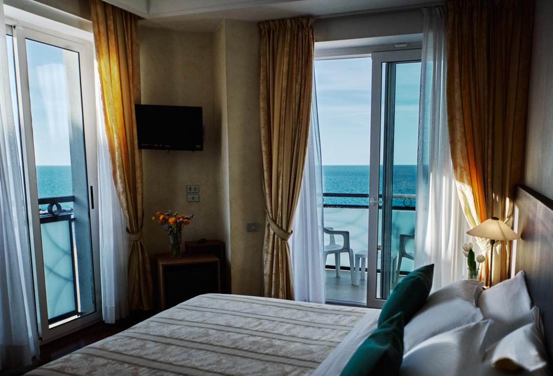 Camera con vista mare, balcone e arredi eleganti.