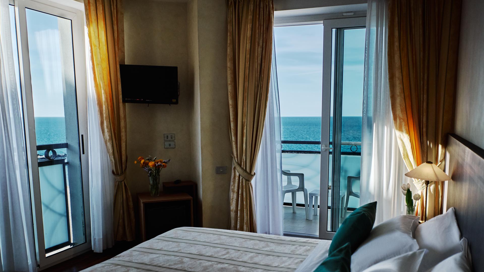 Camera con vista mare, balcone e arredi eleganti.
