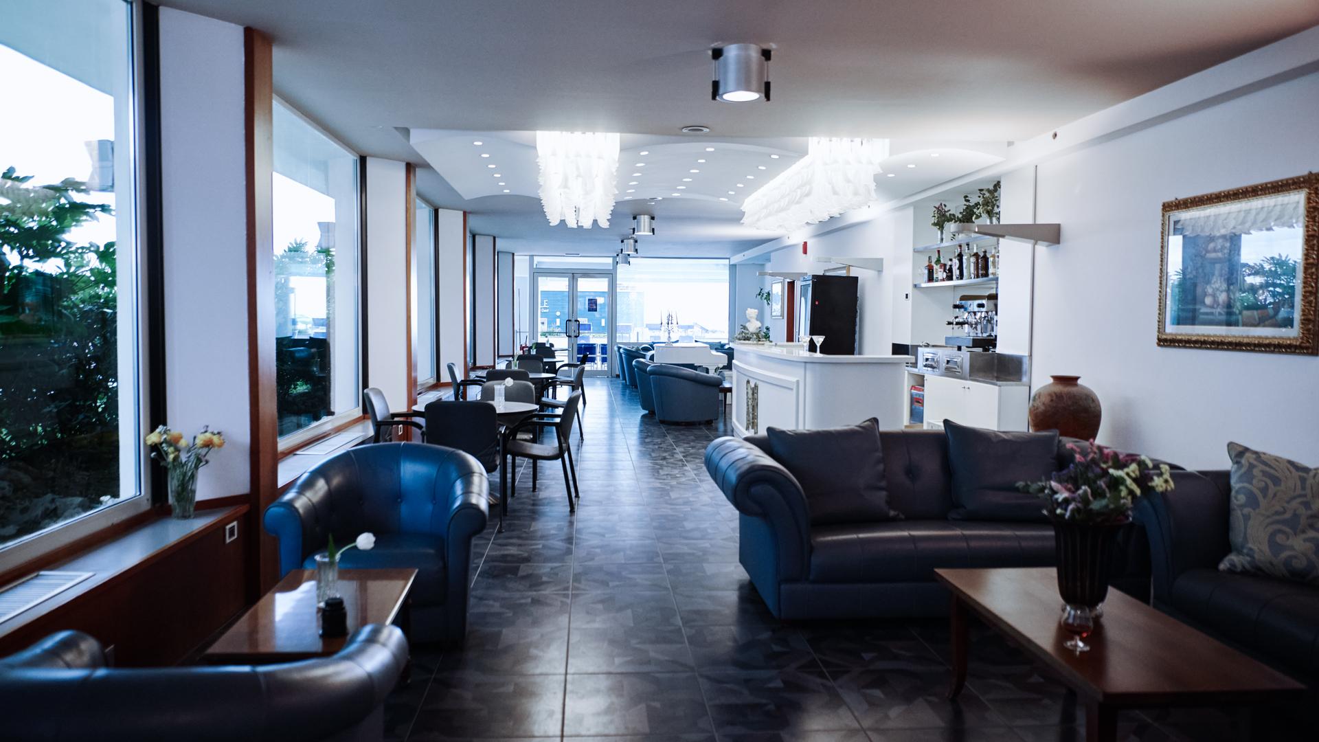 Salon élégant avec canapés, tables et bar lumineux.