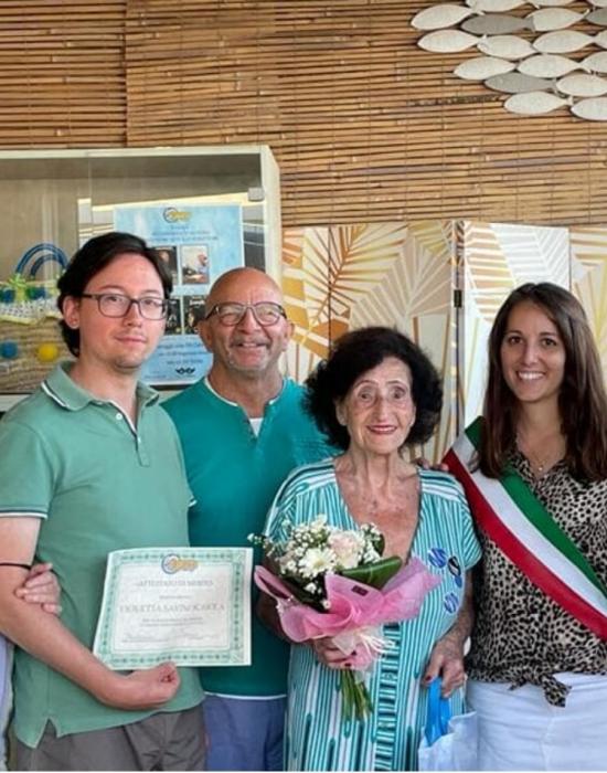 Smiling group with flowers and certificate, celebratory event.