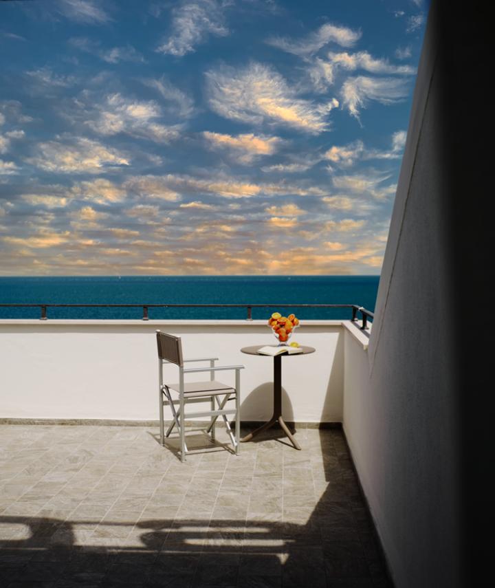 Terrazza con sedia, tavolo e vista mare al tramonto.