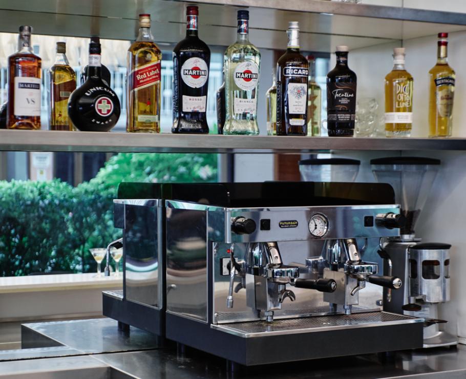 Machine à café avec bouteilles de liqueur et décorations vertes.